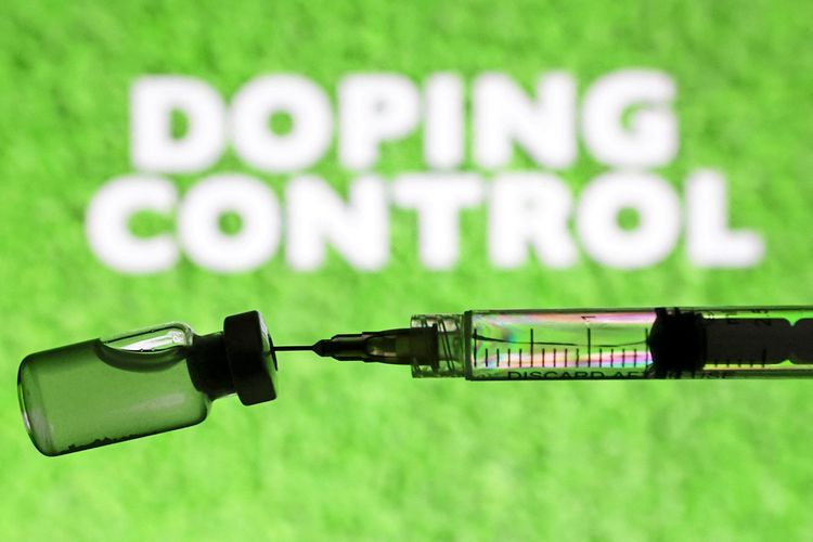 Eine Spritze und ein Fläschchen vor grünem Hintergrund, mit den Worten „Doping Control“ im Hintergrund.
