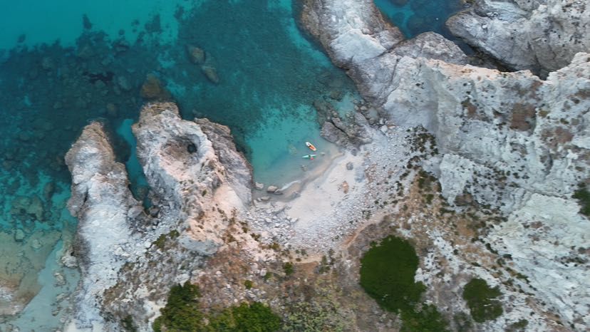 Luftaufnahme einer felsigen, abgelegenen Bucht mit kleinem Sandsttrand und türkisfarbenem Meer