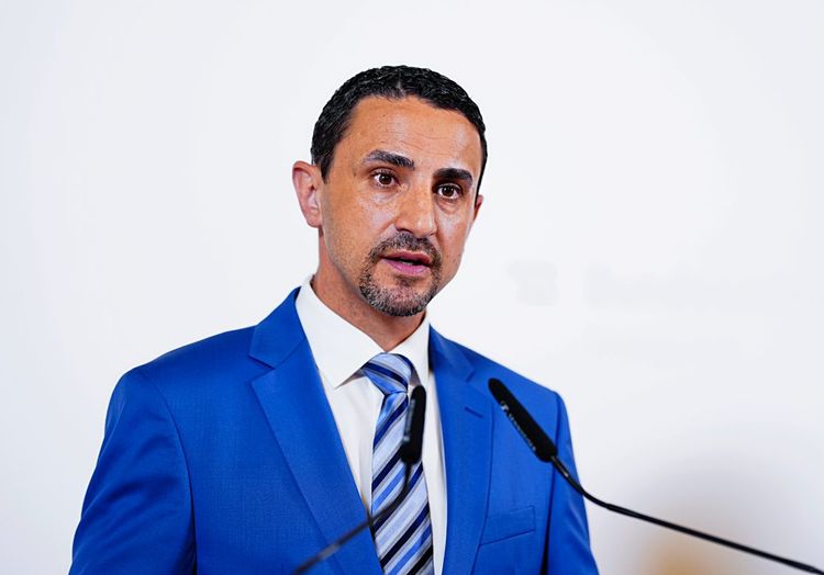 Omar Haijawi-Pirchner vor Mikrophonen bei einer Pressekonferenz.