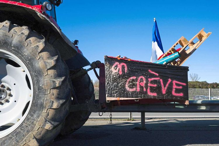 Ein Traktor hat ein Schild mit dem Wort Streik an einer Anhängevorrichtung montiert. 