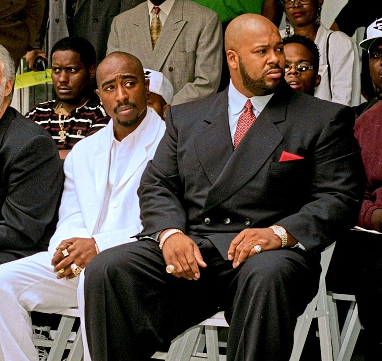 US-Rapper Tupac Shakur und Death-Row-Records-Chef Marion 'Suge' Knight sitzen in Anzügen nebeneinander