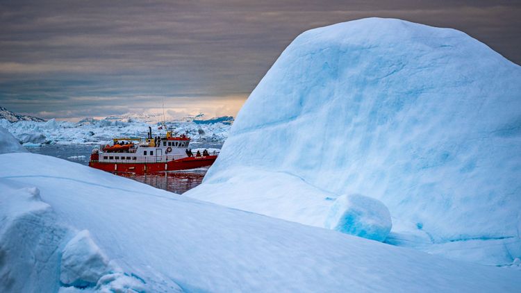 Bei unserer Reise im Juni 2023 nach Ilulissat/Grönland waren wir von den imposanten Eisbergen zutiefst beeindruckt. Das rote Schiff gibt dem Bild den passenden Kontrast. 