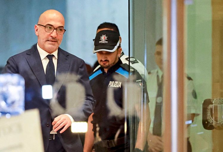 Eine Szene zeigt einen Mann im Anzug, der aus einem Gebäude tritt, begleitet von Polizisten in Uniform.
