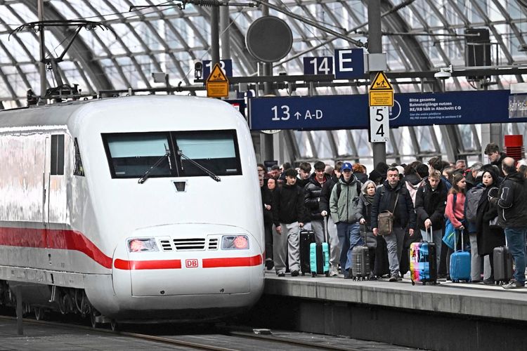 Ein ICE-Zug der Deutschen Bahn steht an einem Bahnsteig im Hauptbahnhof Berlin. Eine große Menschenmenge mit Koffern wartet auf dem Bahnsteig. Schilder zeigen die Gleisnummern 13 und 14.