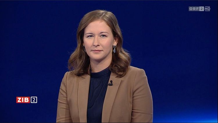 Frau mit langen brauen Haaren und braunem Sakko schaut in die Kamera vor nachtblauem Hintergrund der ZiB 2.