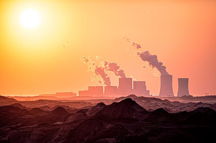 Die Silhouette eines Kohlekraftwerks ist im Sonnenuntergang zu sehen.