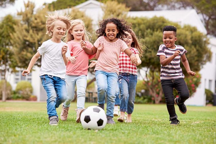 Fünf Kinder unterschiedlicher Ethnien spielen gemeinsam Fußball