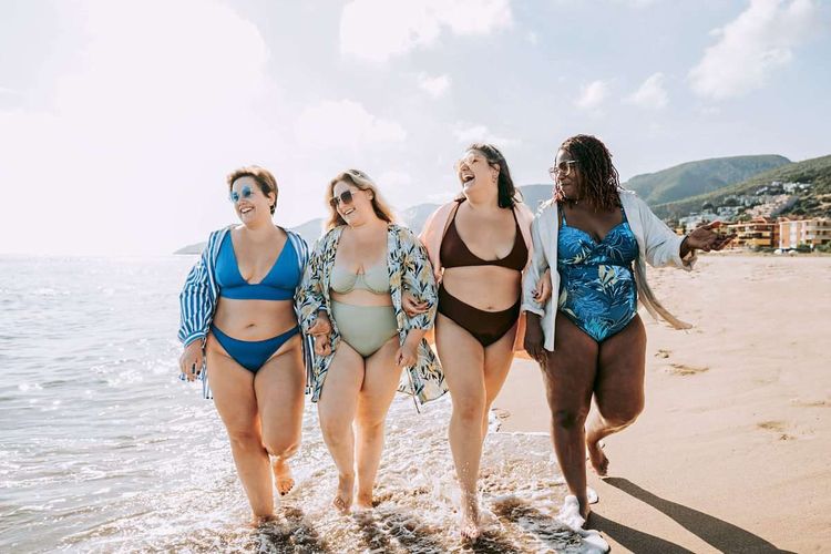 Vier junge, mehrgewichtige Frauen im Bikini am Strand