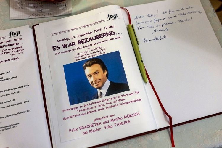 Eine aufgeschlagene Veranstaltungsbroschüre für eine Gedenkveranstaltung zum 100. Geburtstag von Peter Alexander im Bezirksmuseum Floridsdorf. Auf der linken Seite ist eine Programmliste, rechts ein Programmheft mit einem Foto von Peter Alexander und handschriftlichen Notizen daneben. Ein Stift liegt auf der Seite.