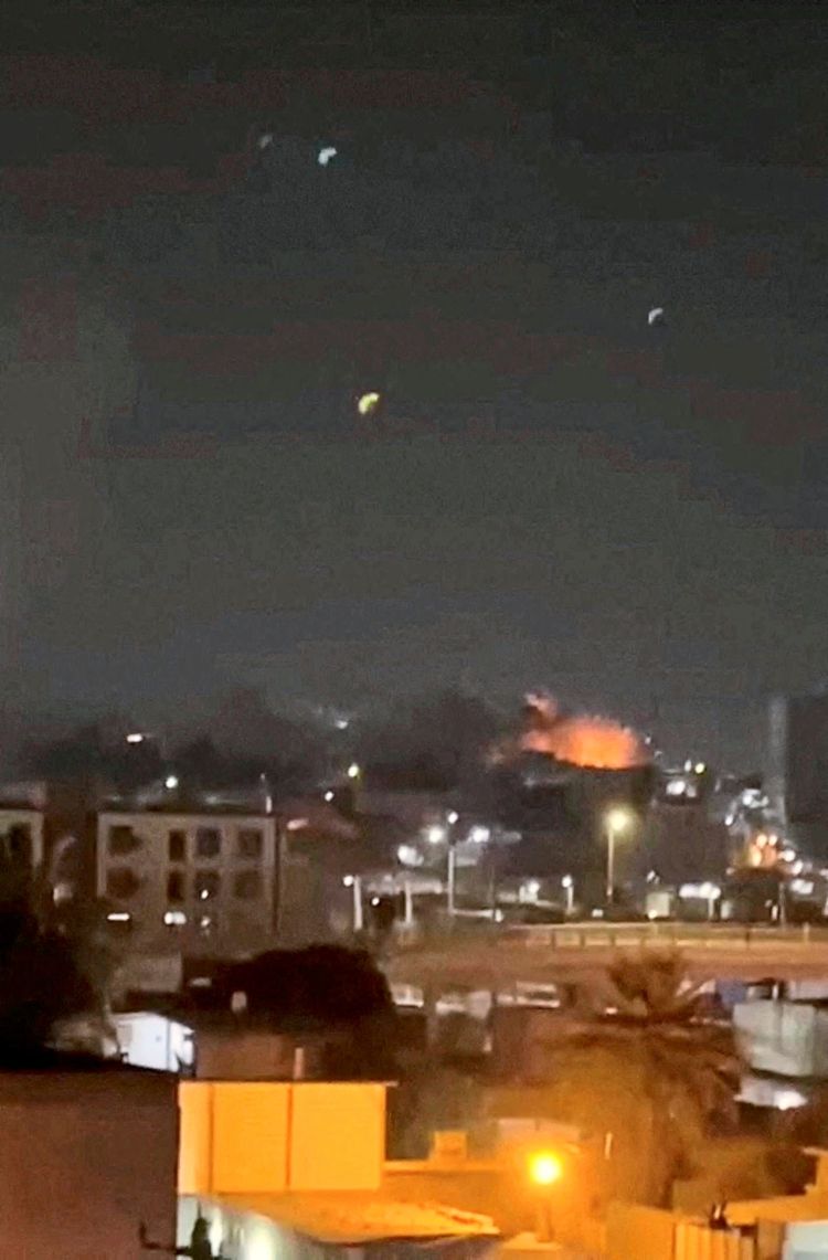 Rauch und Flammen steigen in der Nacht nach einer Explosion in Bandar Abbas, Provinz Hormozgan, Iran, auf. Im Vordergrund sind beleuchtete Straßen, Gebäude und Palmen erkennbar.