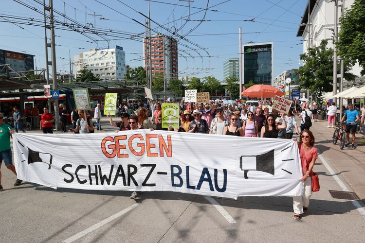 Eine Gruppe Demonstrantinnen und Demonstranten protestiert am 29. Mai gegen die Koalition von ÖVP und FPÖ in Salzburg. Zu sehen ist ein großes Banner mit der Aufschrift 