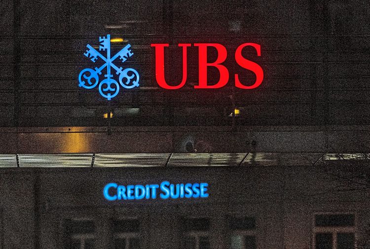 Das rote Logo der UBS und klein darunter der blaue Schriftzug der Credit Suisse