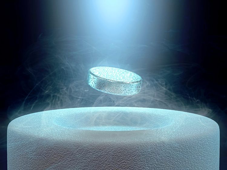 Eine kleine Pille eines supraleitenden Materials schwebt über einem großen Ringmagneten.