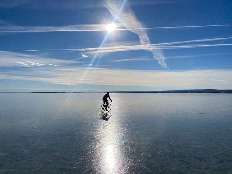 Ein Mann mit einem Fahrrad auf einem zugefrorenen See.