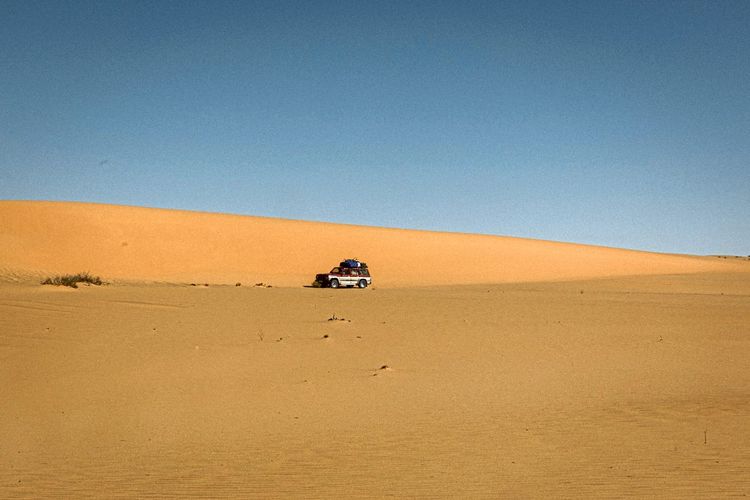 Ein Geländewagen fährt zwischen Sanddünen