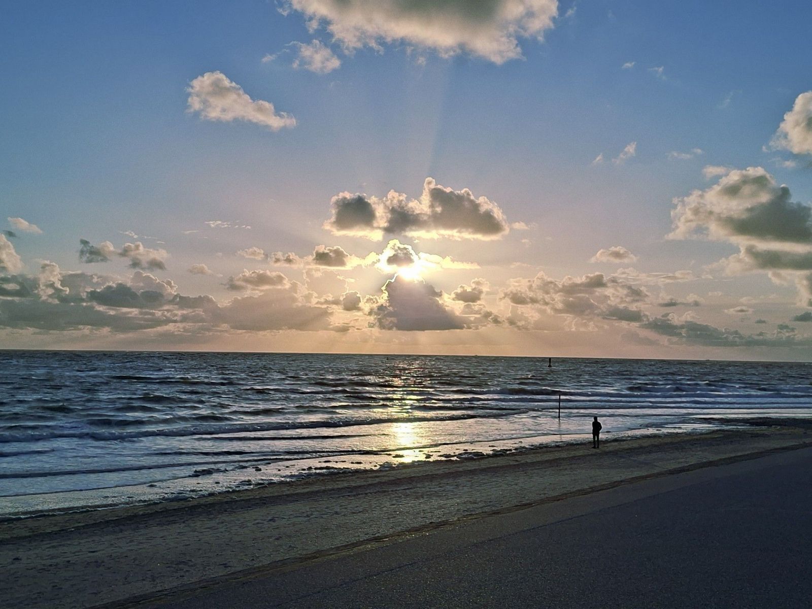 Ein einzelner Mann am Strand beobachtet, wie die Sonne im Meer versinkt