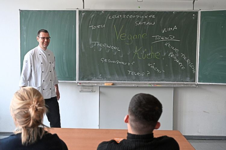 Lehrkraft schreibt Wortmeldungen der Schülerinnen und Schüler zum Thema vegane Küche an die Tafel