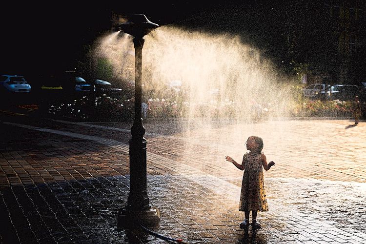 Ein Mädchen steht unter einer Sprühnebeldusche im polnischen Krakau
