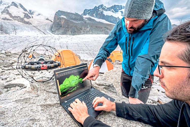 Menschen am Gletscher vor Laptop und Drohne