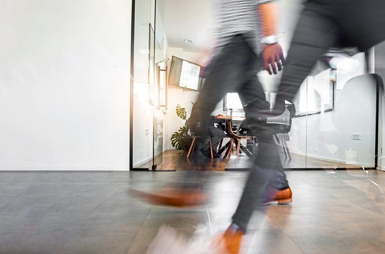 Personen gehen durch modernes Bürogebäude, Beine sind in Bewegung