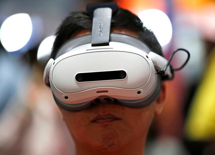 Ein Besucher nutzt eine Virtual-Reality-Brille, um mehr über den Weltraum und die Galaxie zu lernen, auf der Nationalen Wissenschafts- und Technologiemesse in Bangkok, Thailand. Im Hintergrund verschwommene Lichter und bunte Farben.