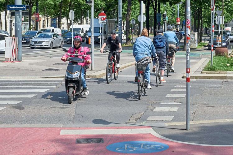 Ein Essenslieferant mit einem E-Mofa auf dem Radweg.