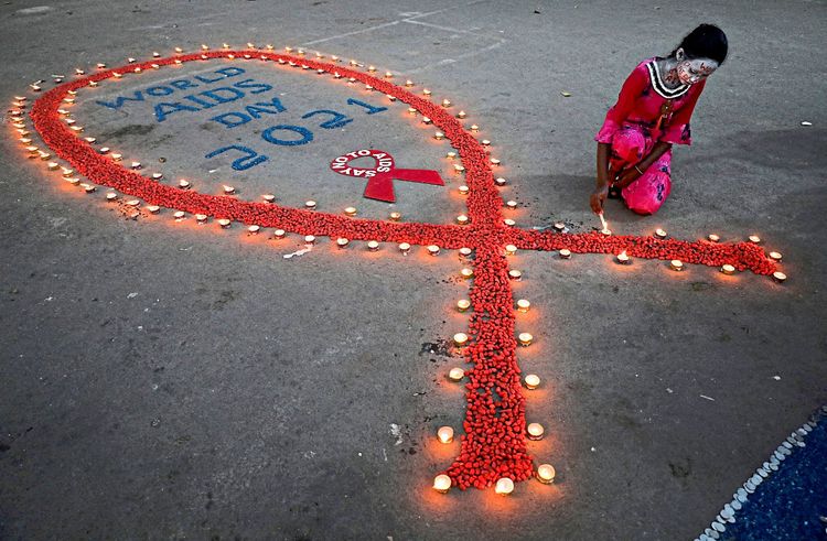 Ein Mädchen in Kalkutta zündet Kerzen rund um eine AIDS-Schleife an.