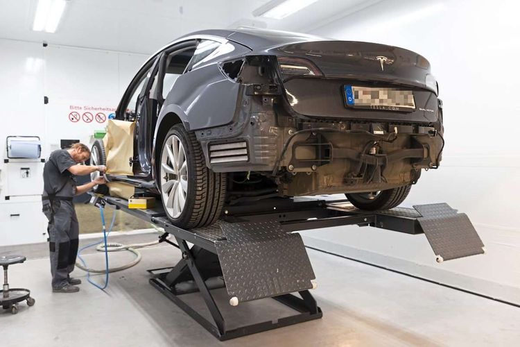 Das Bild zeigt ein E-Auto von Tesla bei der Reparatur