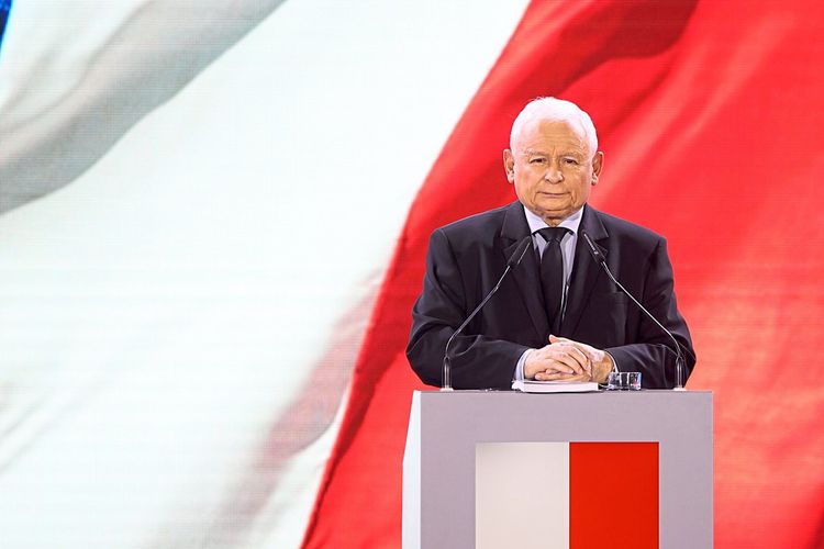 Jarosław Kaczyński hinter dem Rednerpult, dahinter eine polnische Fahne.