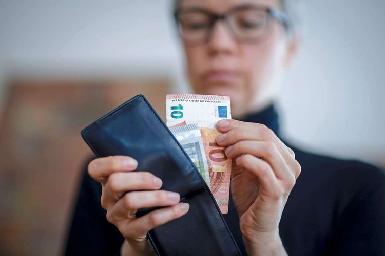 Eine Frau nimmt Geldscheine aus einer Geldbörse