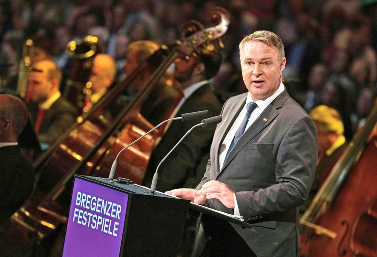 Ein Mann im Anzug spricht bei der Eröffnung der Bregenzer Festspiele am Rednerpult mit der Aufschrift 
