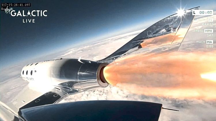 Virgin Galactic Flug mit Blick auf eine feurige Antriebsdüse und über die Wolkendecke