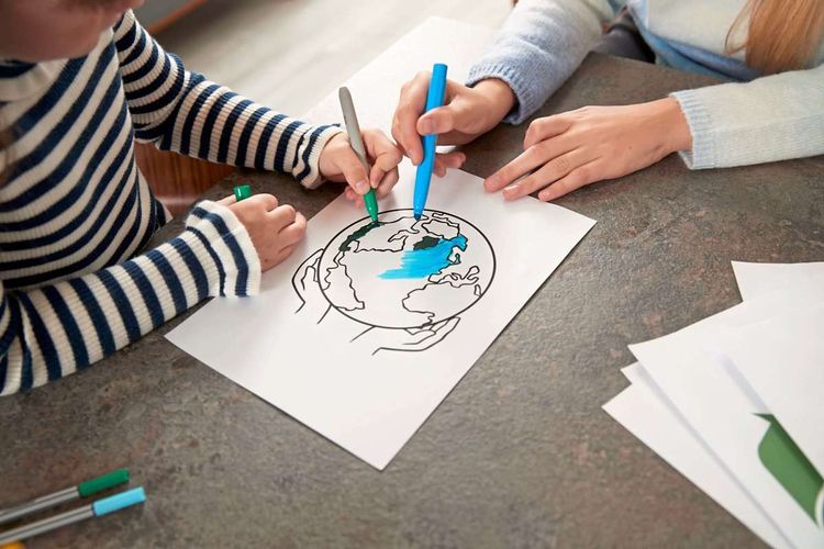 Kinder kolorieren eine Weltkarte mit Blau- und Grünstiften