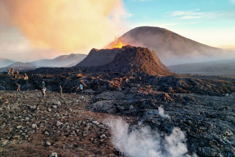 Eine Menschengruppe rund um einen Vulkan