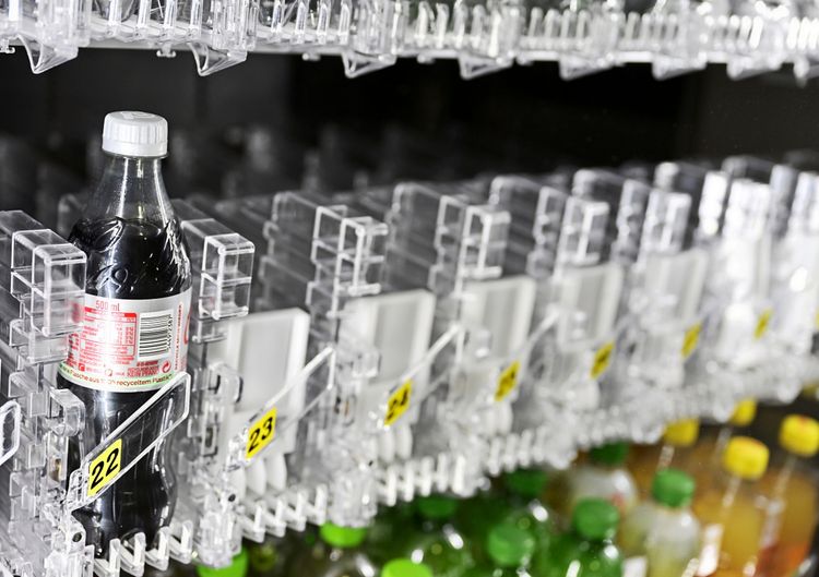 Eine 0,5-Liter-Flasche Coca-Cola light in einem Getränkeautomaten. Nur eine Flasche ist im Fach mit der Nummer 22 sichtbar, umgeben von leeren Fächern und Flaschen anderer Getränkearten.