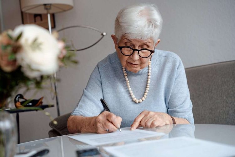 Ältere Frau schreibt auf einem Zettel