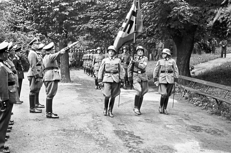 Marschierende Soldaten mit Hakenkreuzfahne, Hitlergruß