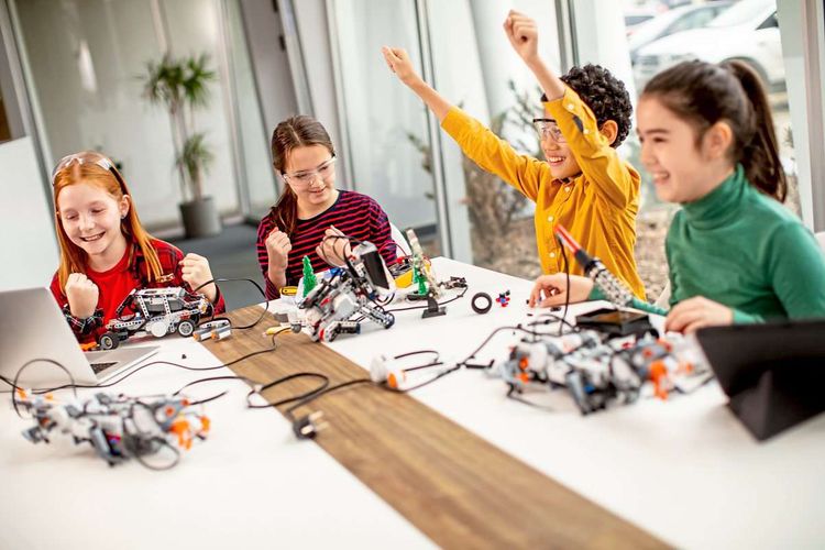Kinder auf einem großen Tisch beim Zusammenbauen von technischen Geräten
