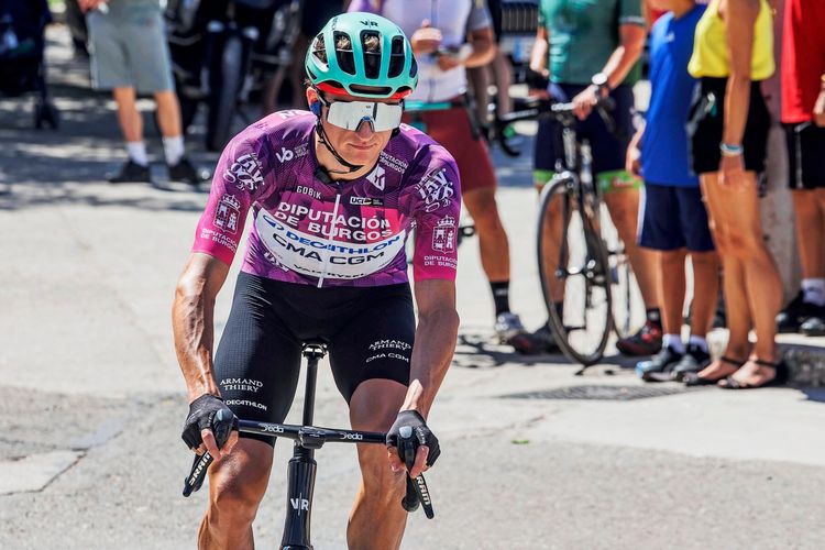 Ein Radrennfahrer des Decathlon-Teams trägt ein lilafarbenes Trikot und wurde während der vierten Etappe der Vuelta a Burgos 2026 in Spanien fotografiert. Im Hintergrund sind Zuschauer und weitere Radfahrer erkennbar.