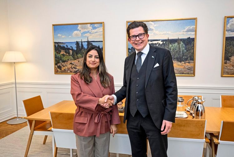 Eine Frau und ein Mann in Anzug schauen in die Kamera und geben sich die Hand.