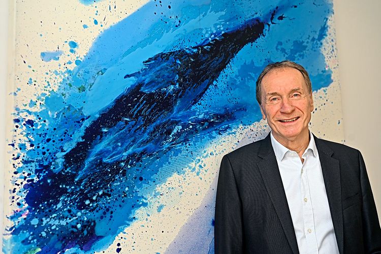 Der Vorstadschef von Schoeller-Bleckmann Oilfield Equipment vor eine in intensiven Blautönen gemalten Bild von Erni Marihart.