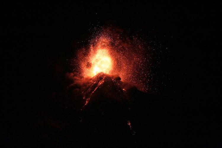 Ein Ausbruch des Vulkans Fuego in der Nähe von Alotenango, Guatemala, bei Nacht. Glühende Lava und aufsteigende Asche sind deutlich sichtbar.