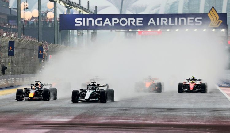 Formel-1-Sprint-Rennen beim Großen Preis von Singapur: Mehrere Rennwagen, darunter Mercedes und Red Bull, fahren durch dichten Wassersprühnebel auf der regennassen Strecke des Marina Bay Street Circuit. Im Hintergrund ist ein Banner von Singapore Airlines zu sehen.