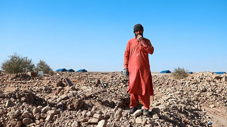 Ein Mann in roter Kleidung steht auf Trümmern