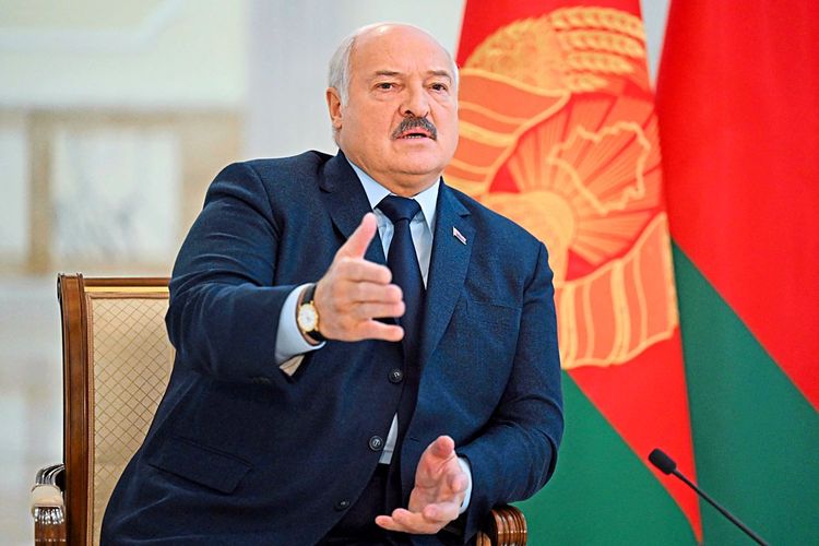 Der belarussische Präsident Alexander Lukaschenko sitzt vor einer Flagge.