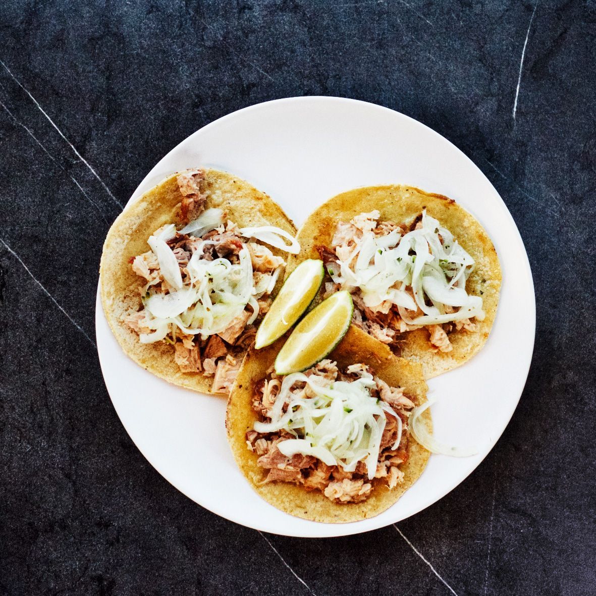 Tacos de Carnitas mit in Orange, Zucker Zimt und Schmalz eingekochter Schweinsschulter und Jalapeño-Zwiebeln