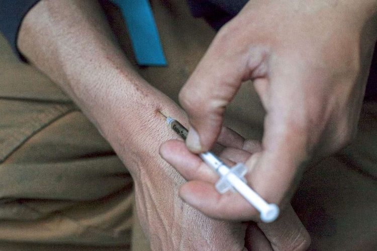 Ein Mann injiziert sich Heroin mit einer Nadel.