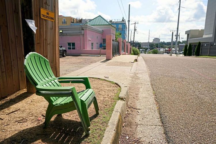 Leerer Sessel  auf Gehsteig vor leerem Straßenzug