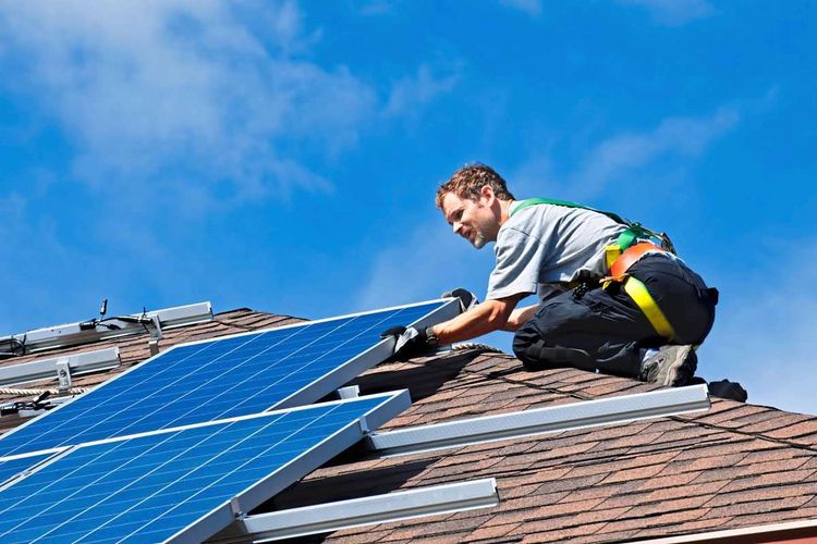 Ein Mann montiert Photovoltaik-Platten auf einem Dach