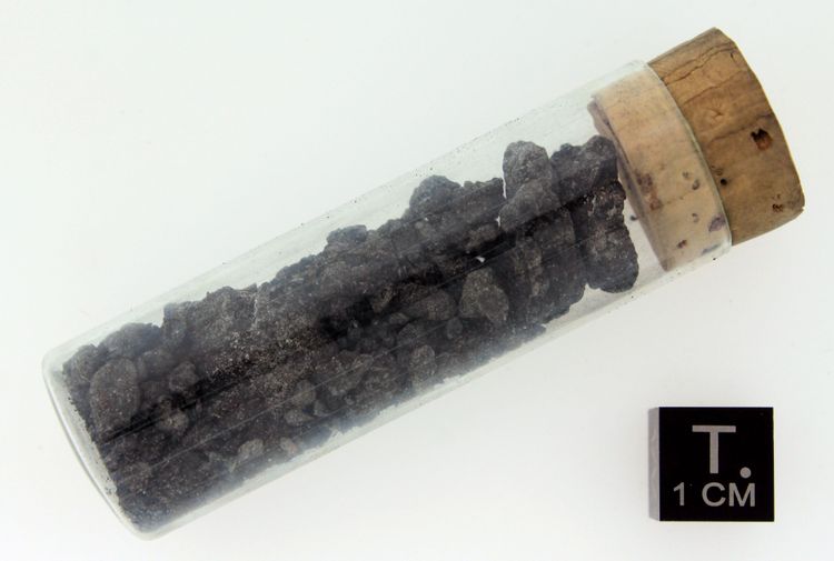 Fragment des Orgueil-Meteoriten im Naturhistorischen Museum Wien NHM. Eine kleine Glasphiole mit Korken enthält schwarze Steinbruchstücke.